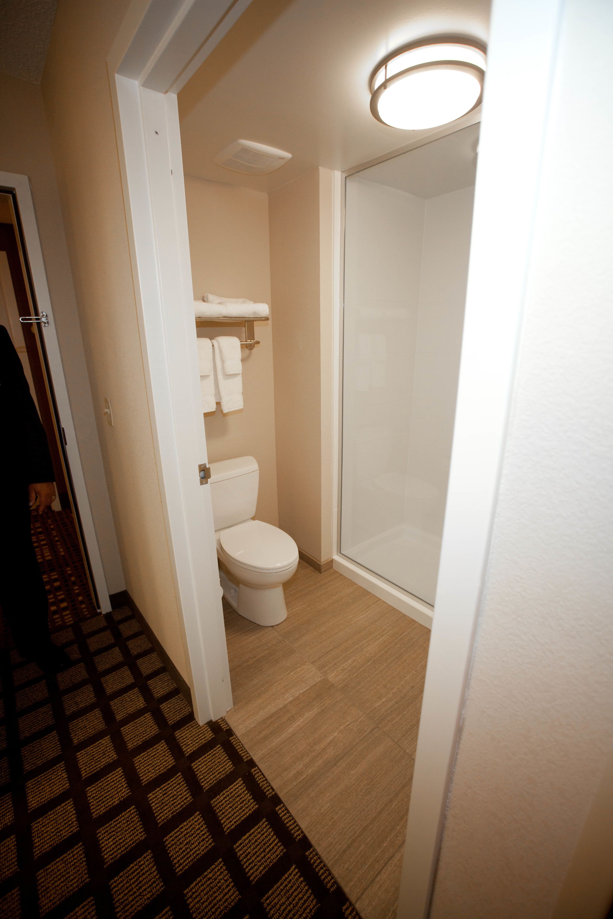 Une salle de bain d’hôtel équipée de toilettes, d’une douche à parois de verre et d’un porte-serviettes avec des serviettes.
