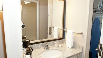 A bathroom with a sink, mirror, towel rack, and a shower area.