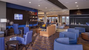 A modern hotel lobby with blue and beige seating, a large TV, and a patterned carpet. - Courtyard Indianapolis Noblesville (Noblesville)
