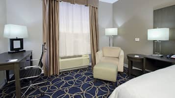 Habitación de hotel con escritorio, dos sillas, una mesita, cama y dos lámparas.