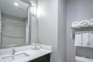 Un baño moderno con lavamanos, espejo y toallero blancos.