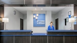 A reception desk with a clock, a Holiday Inn Express sign, and a non-smoking property notice. - Holiday Inn Express & Suites Houston North - IAH Area by IHG (Houston)