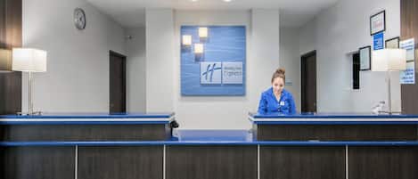 A reception desk with a clock, a Holiday Inn Express sign, and a non-smoking property notice.