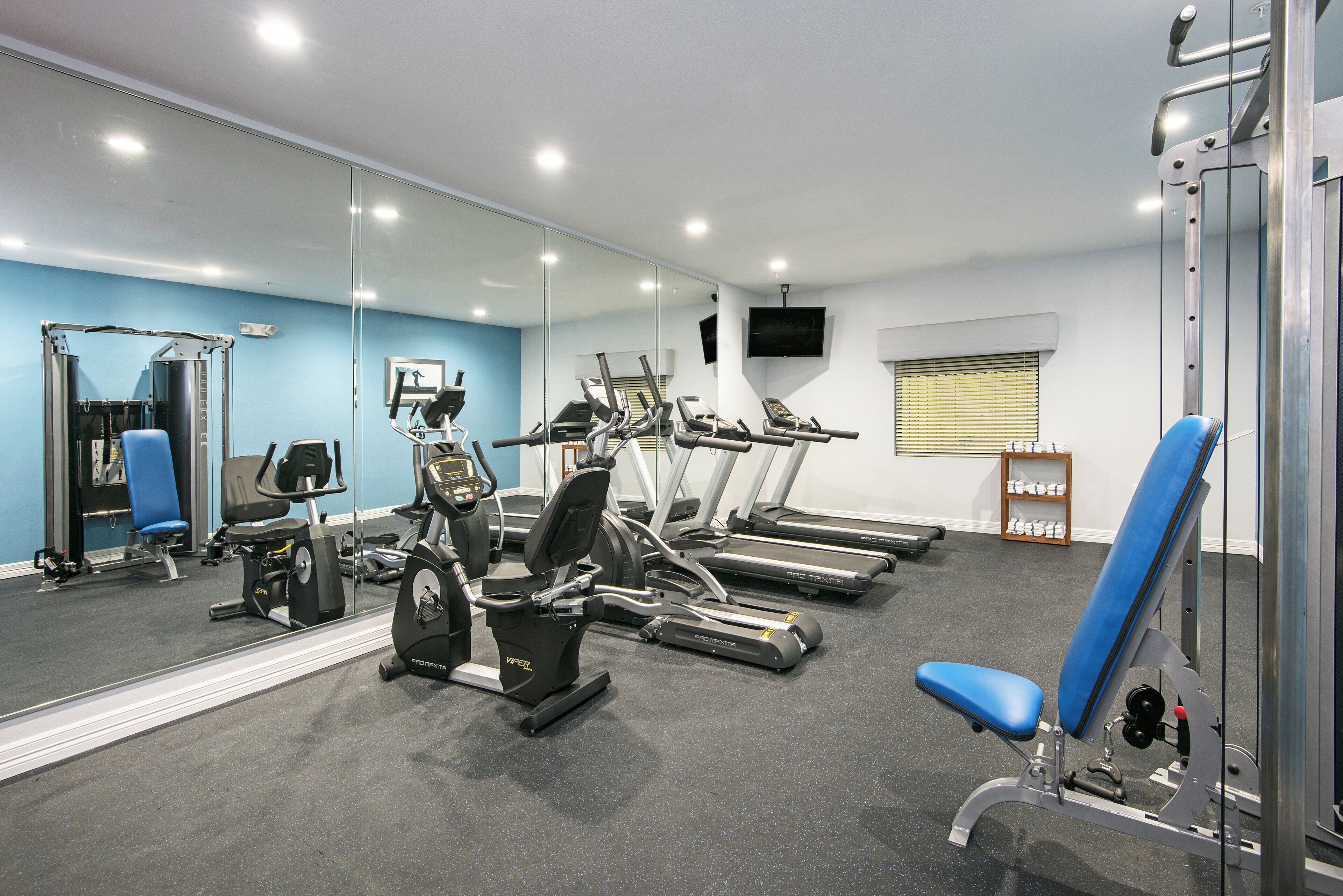 A gym with exercise equipment, a television, and a mirror.