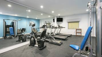 A gym with exercise equipment, a television, and a mirror.
