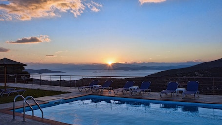 Una piscina al aire libre, sombrillas, sillones reclinables de piscina
