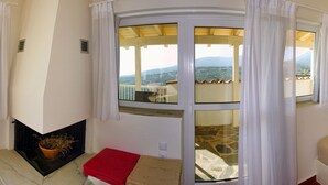 Une pièce dotée d’une porte en verre incurvée qui donne sur un balcon offrant une vue sur un paysage montagneux.