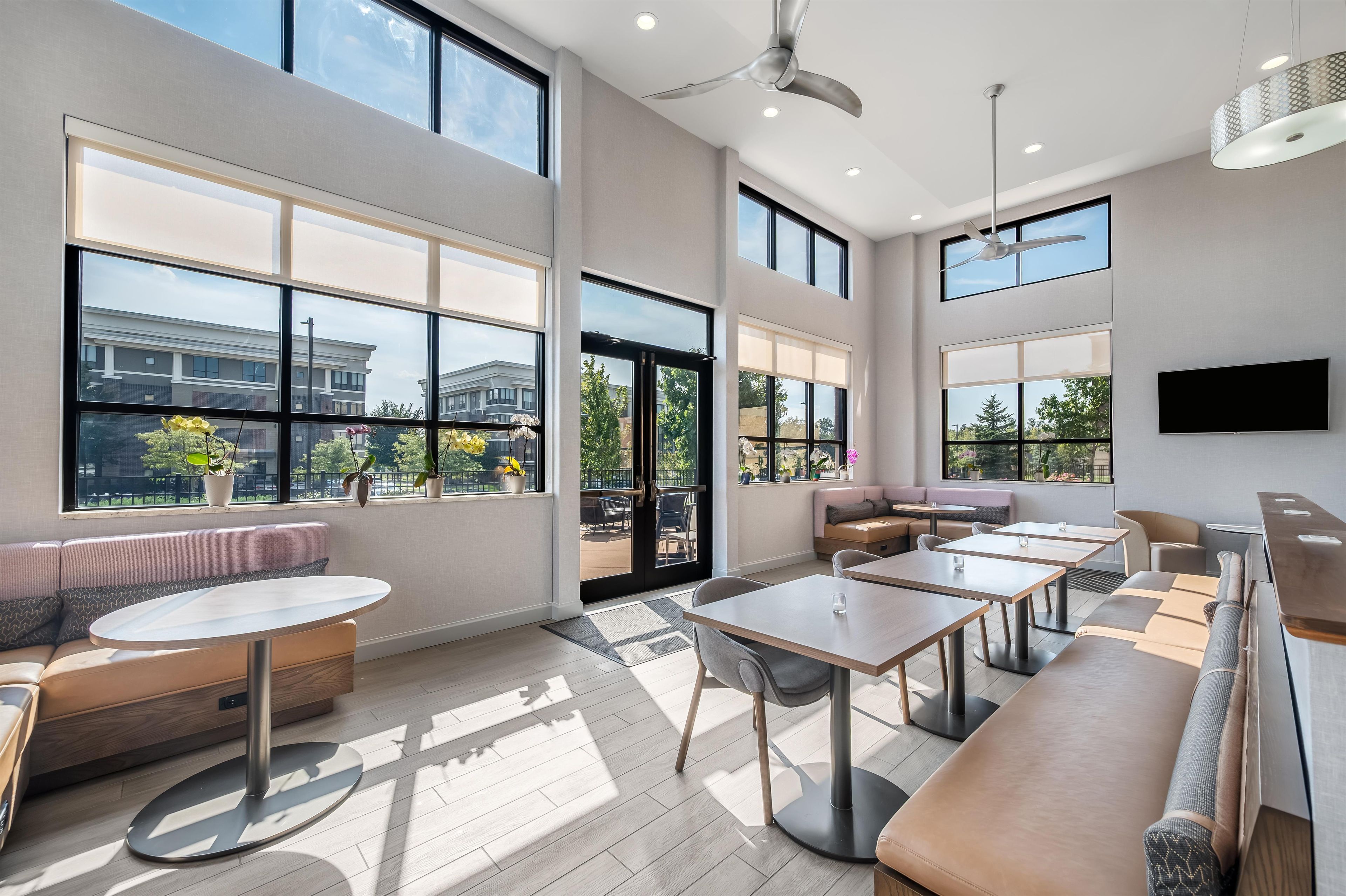 A modern interior with large windows, a seating area, and a flat-screen TV.