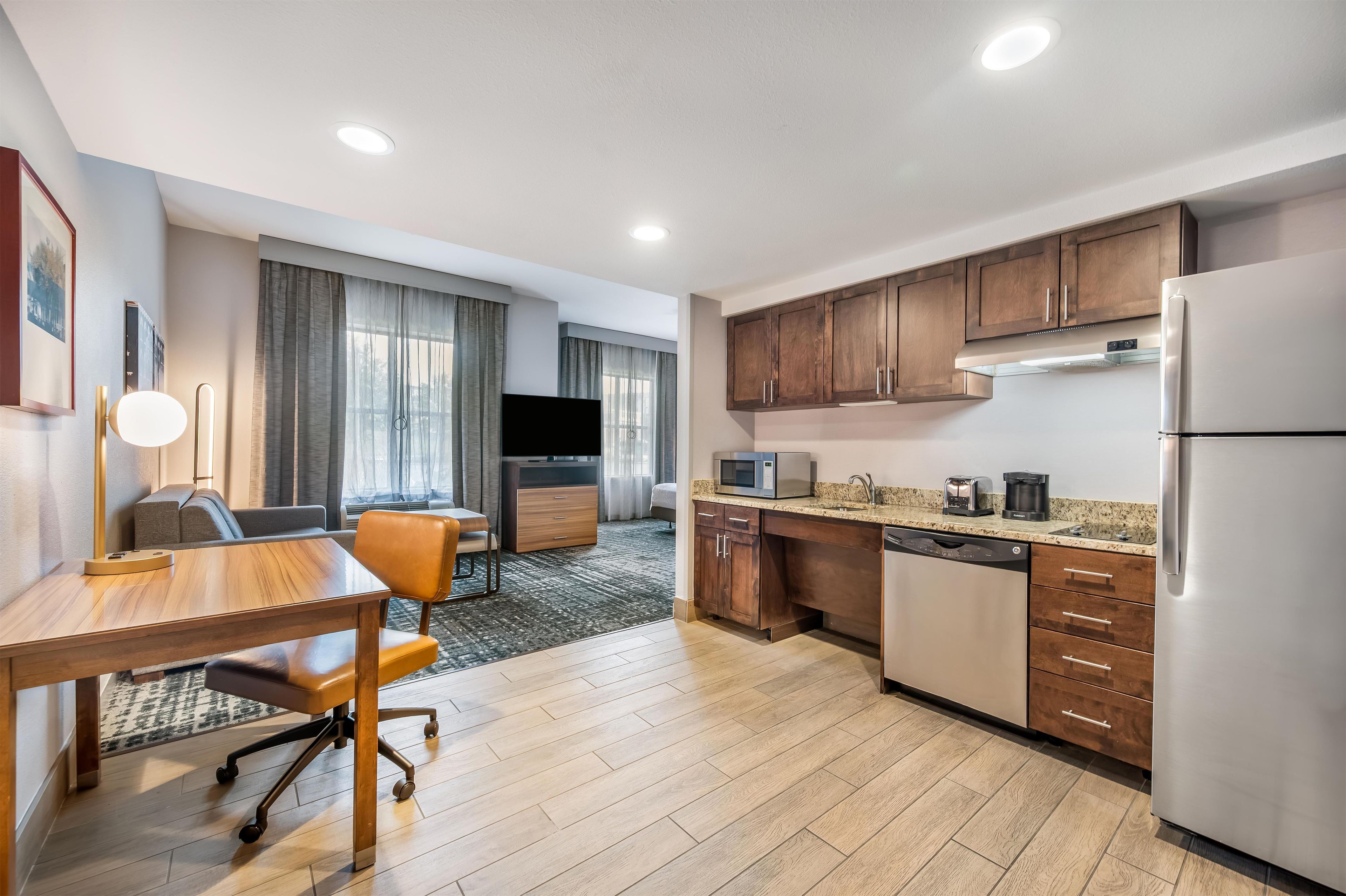 A modern kitchen with wooden cabinets, a stainless steel refrigerator, and a dining area with a table and chairs.