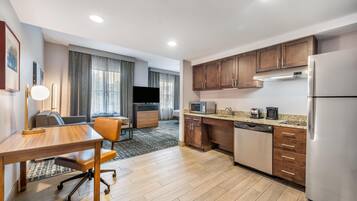 A modern kitchen with wooden cabinets, a stainless steel refrigerator, and a dining area with a table and chairs.