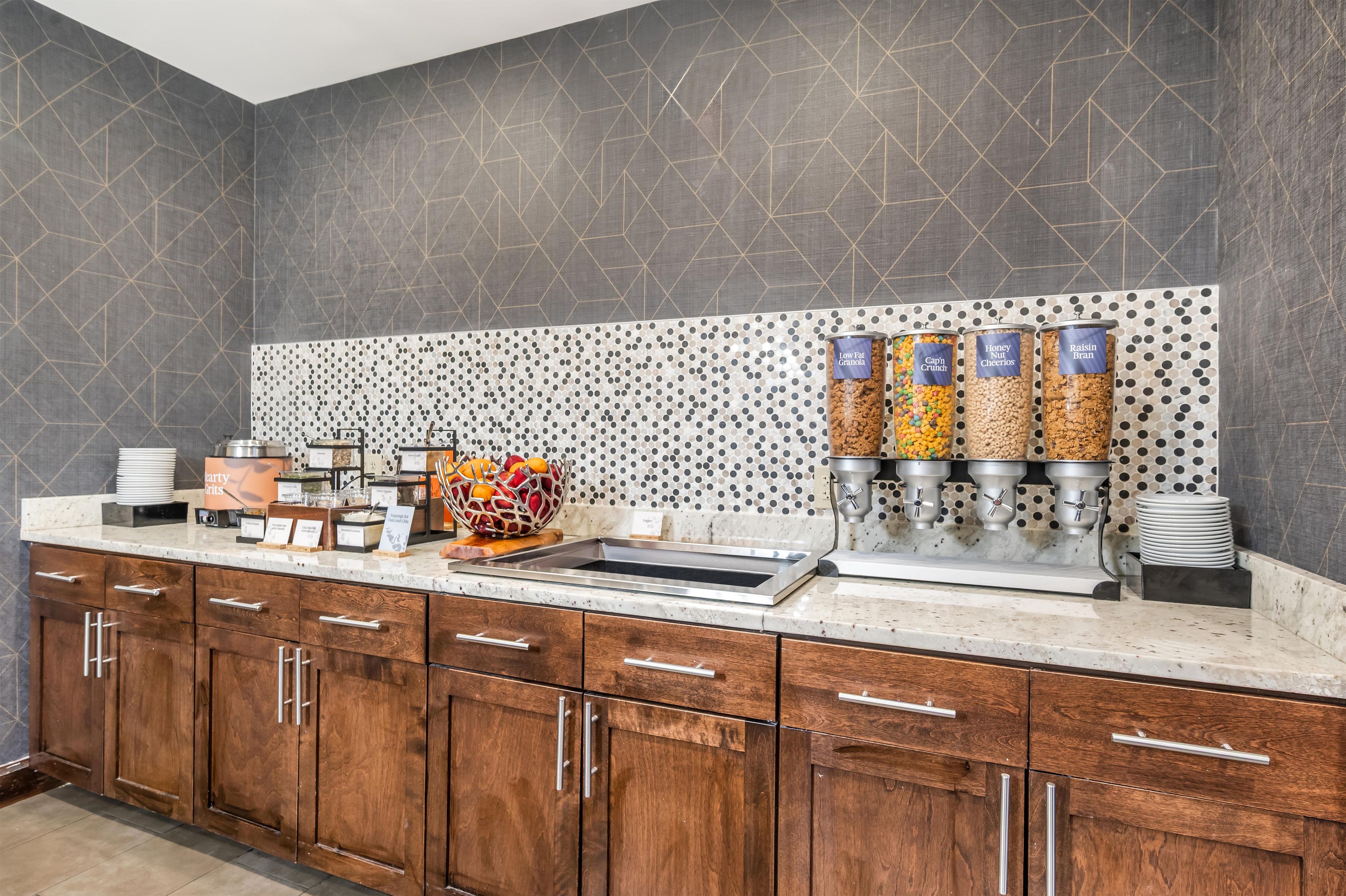 A breakfast bar with a variety of food options, including granola, cereal, and fruit.