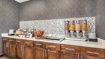 A breakfast bar with a variety of food options, including granola, cereal, and fruit.