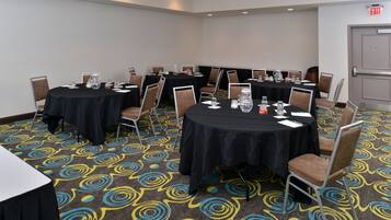 Un salón de conferencias con mesas redondas, sillas y piso alfombrado.