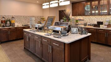 A modern kitchen with a central island, built-in cabinets, and a chalkboard menu.