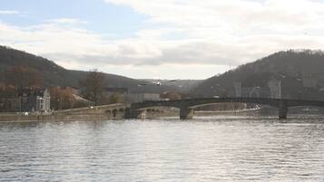 A stone bridge over a river with buildings and hills in the background.