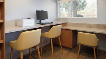 Una cocina con mostrador, una computadora y tres sillas.