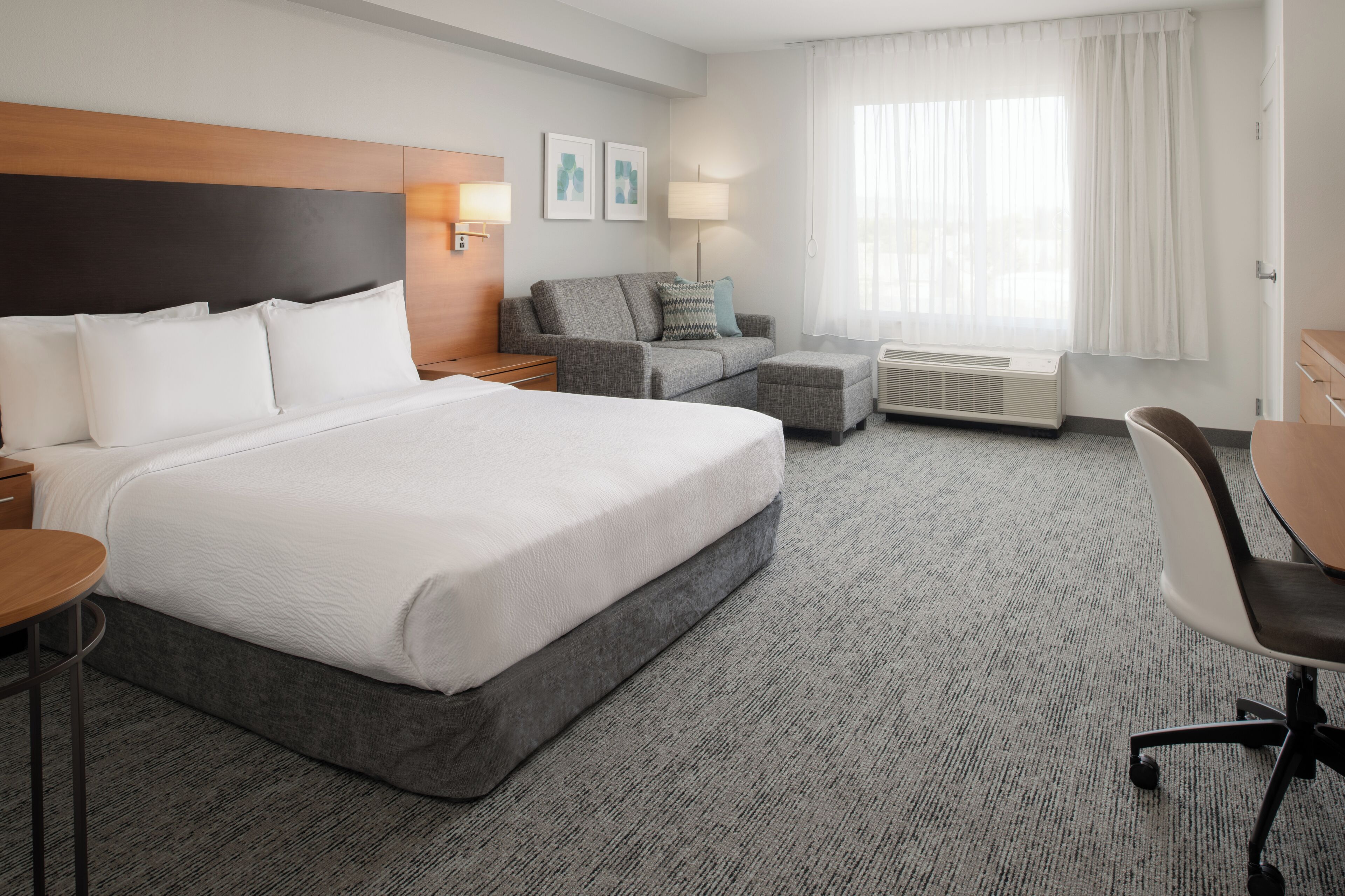 A hotel room with a large bed, a sofa, a desk, and a chair.