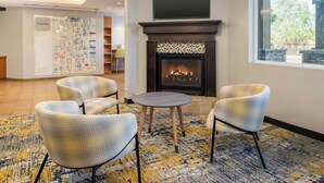 A modern lounge area with a fireplace, seating, and a large map on the wall. - TownePlace Suites by Marriott Lancaster, CA (Lancaster)