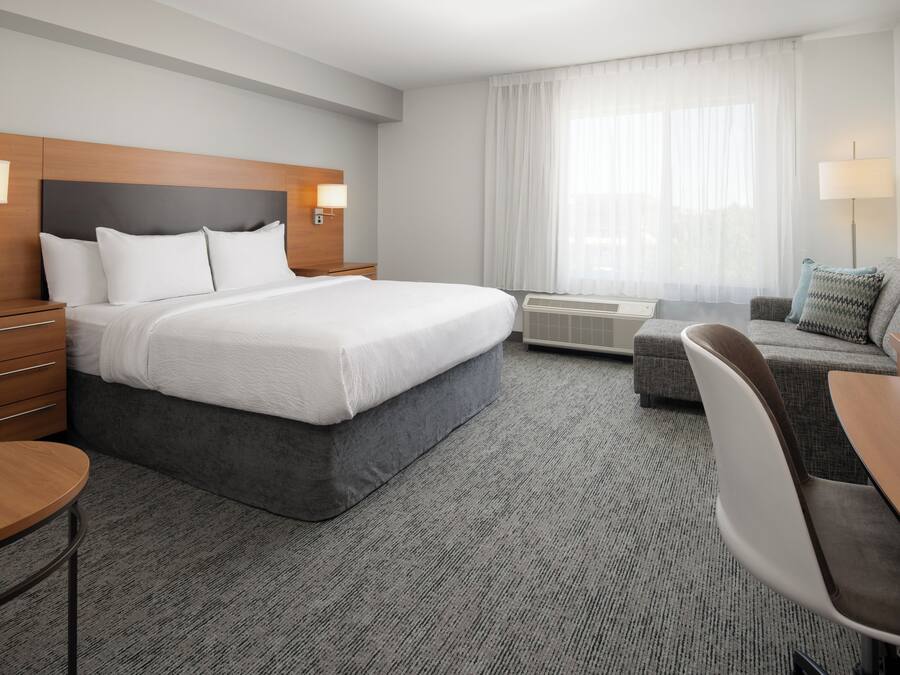 Een hotelkamer met een groot bed, een bureau, een stoel, een bank en een raam met gordijnen.