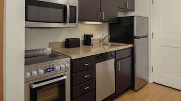 Una cocina compacta equipada con microondas, tostadora, cafetera, lavavajillas, horno y refrigerador.