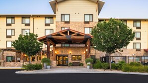 A multi-story hotel with a stone facade, a covered entrance, and a pool area visible in the background. - TownePlace Suites by Marriott Lancaster, CA (Lancaster)