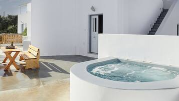 Un edificio moderno blanco con jacuzzi y mobiliario de madera en el exterior.
