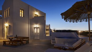 Ein modernes Gebäude mit einer Terrassenanlage, darunter ein Whirlpool, Liegestühle und ein Tisch mit einer Ananas.