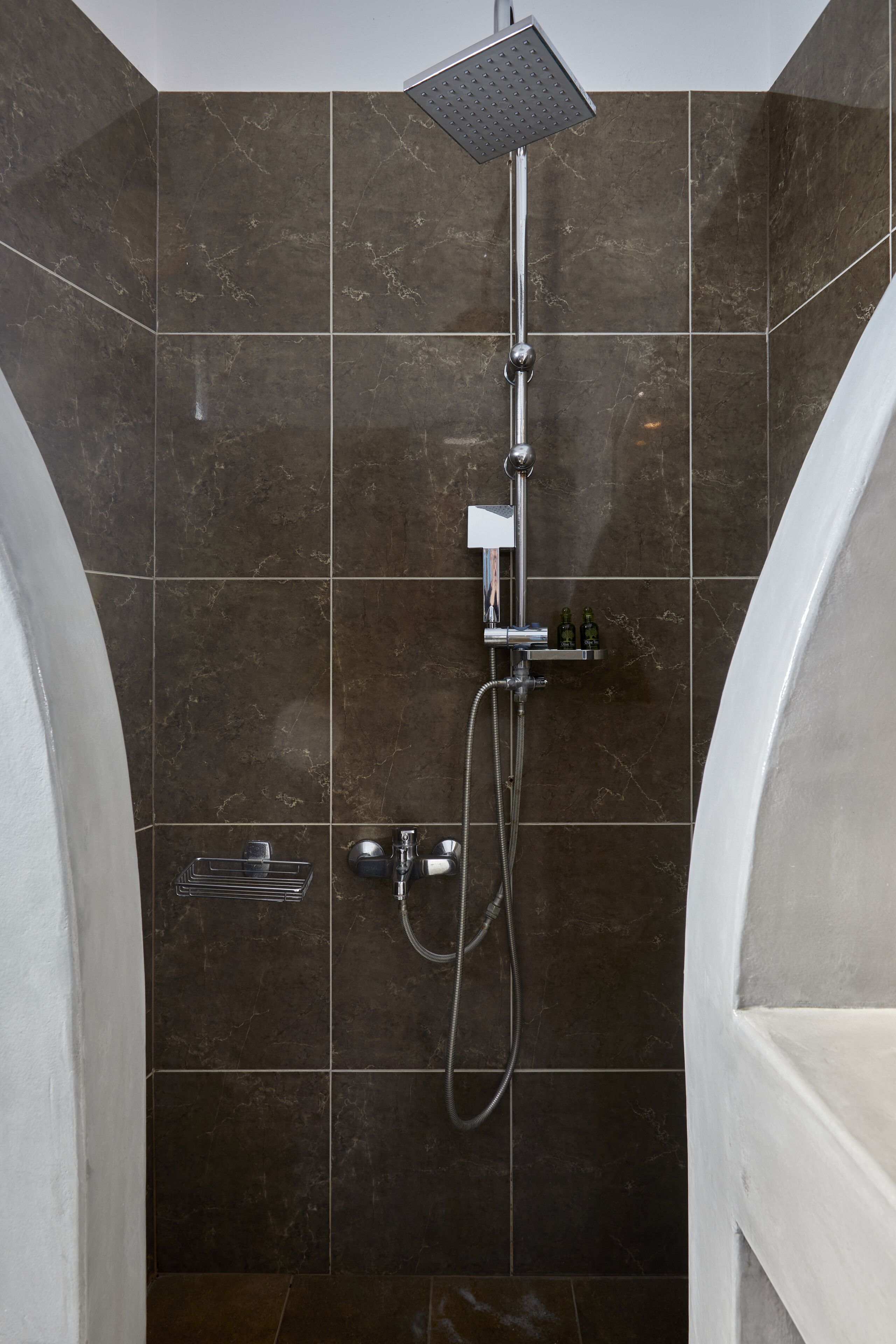 Un baño moderno con ducha, cabezal de ducha manual, grifo de mano y barra para toallas.