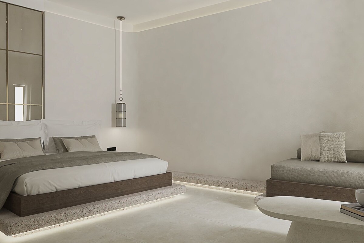 A modern bedroom with a bed, a sofa, and a small table with a book and a bowl.