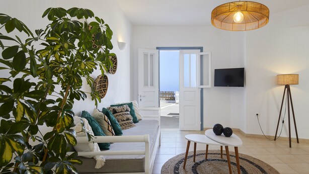 Ein modernes Wohnzimmer mit einem weißen Sofa, einem runden Tisch und einer großen Pflanze.