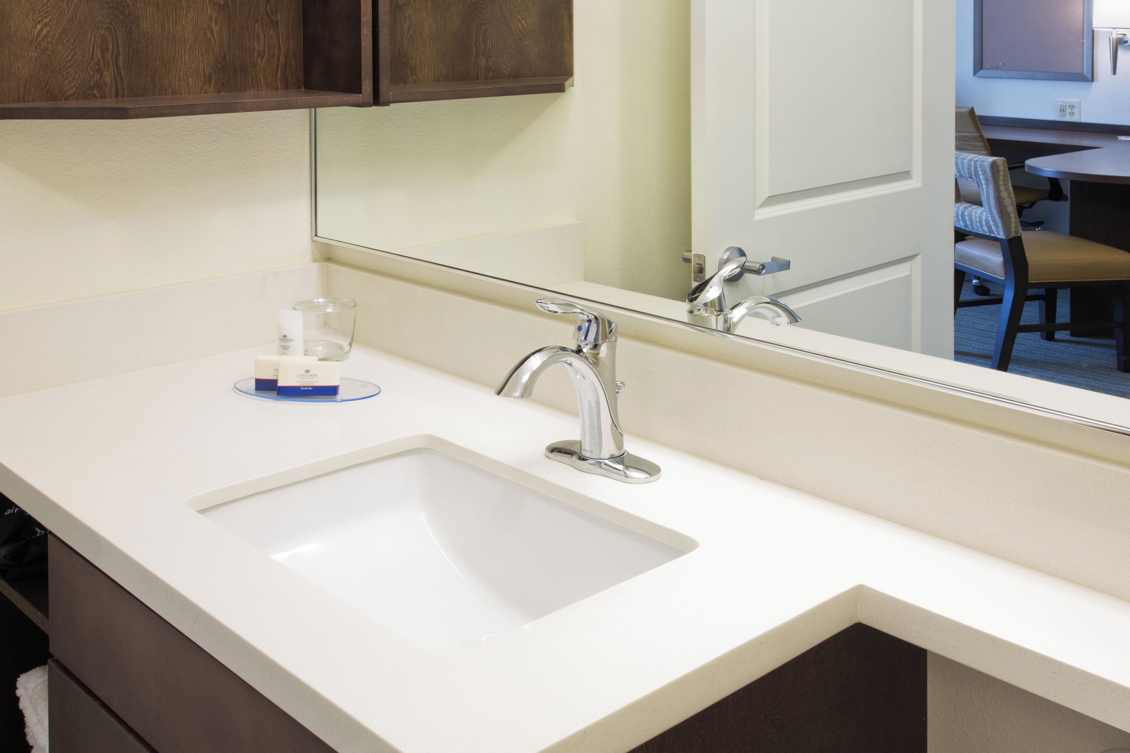 A bathroom with a white sink, a mirror, and a wooden cabinet above it.