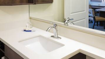 A bathroom with a white sink, a mirror, and a wooden cabinet above it.