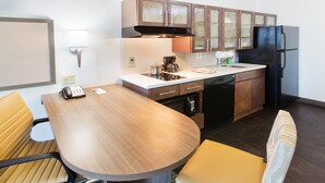 Una cocina compacta con una mesa redonda, dos sillas, cafetera y refrigerador.