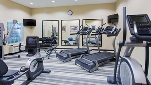 Gimnasio de hotel con cintas de correr, elíptica y pesas libres.