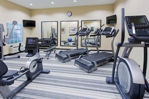 A hotel fitness center with treadmills, an elliptical, and free weights.