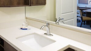 Un baño con lavamanos blanco, espejo y armarios de madera.