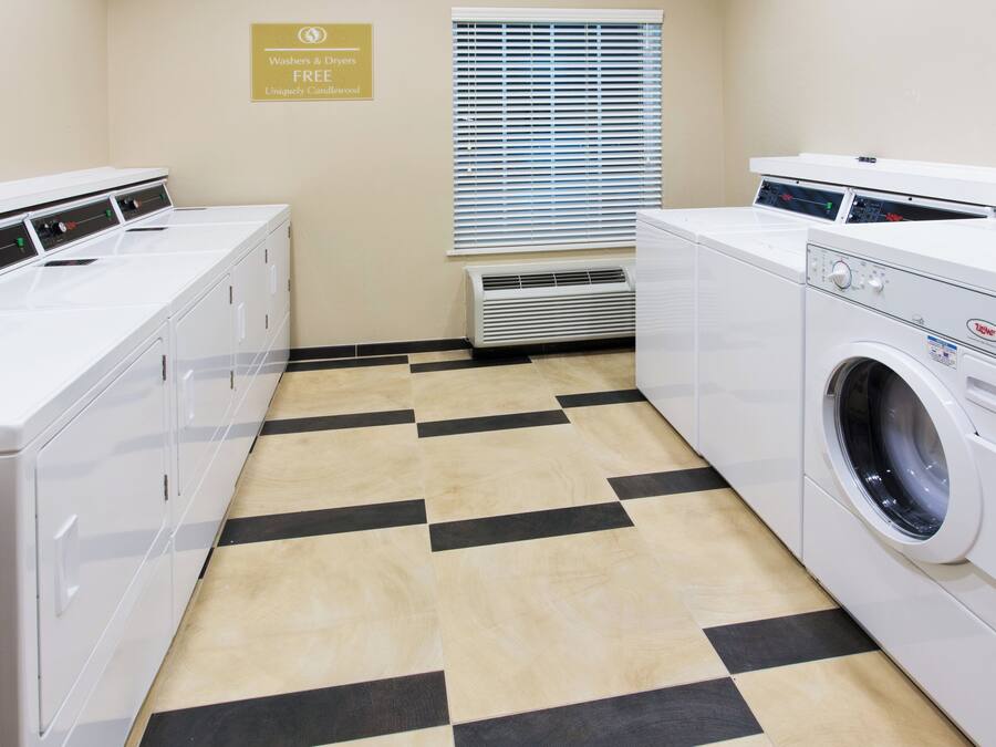 A laundry room with a checkered floor, a sign indicating free washers and dryers, and a window with blinds.