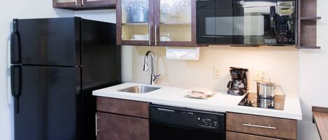 A compact kitchen with a refrigerator, dishwasher, microwave, and a coffee maker.