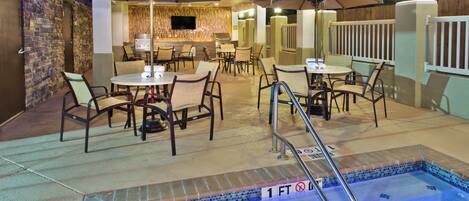 Zona de piscina exterior con jacuzzi, asientos y sombrillas.