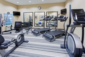 Un gimnasio de hotel con cintas de correr, elíptica y pesas sueltas.