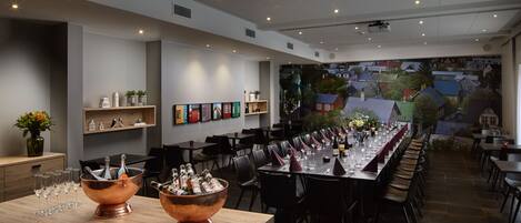 A restaurant with a long dining table, multiple chairs, and a bar area with copper buckets of bottles.