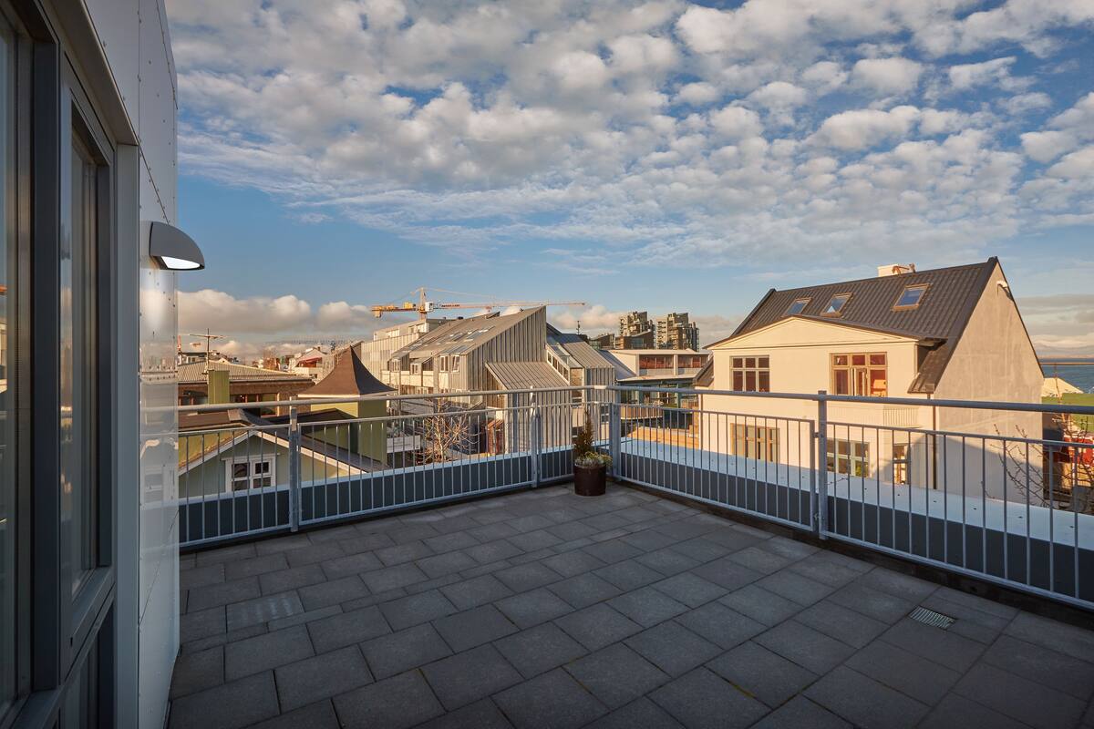 A balcony with a view of surrounding buildings and a crane in the distance.