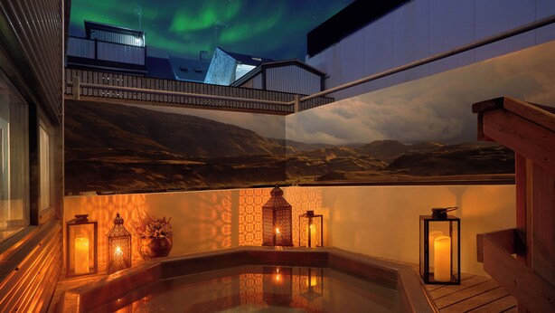 Un jacuzzi con barandillas de madera, rodeado de faroles y un mural pintoresco.