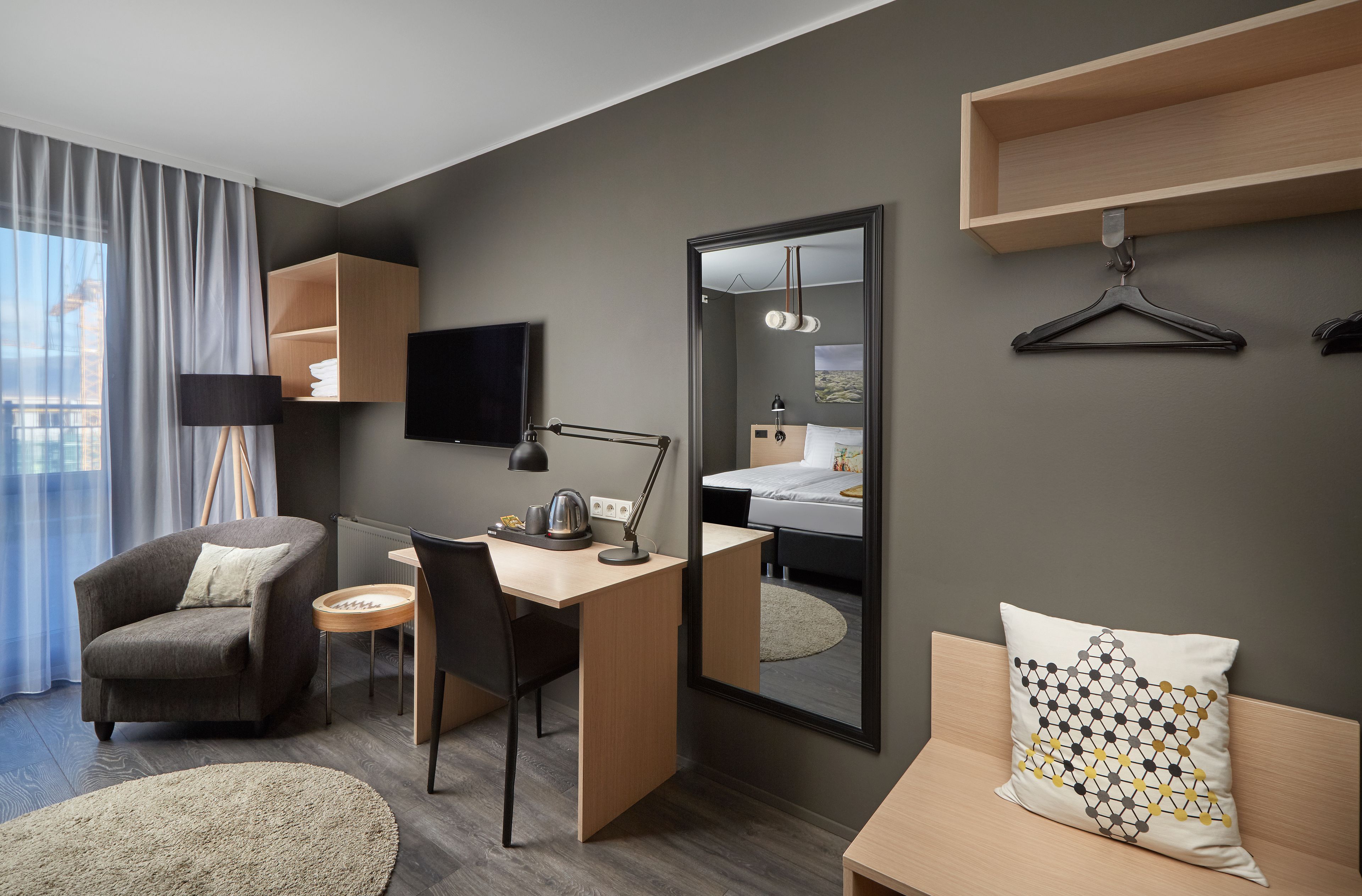 Quarto de hotel moderno com escrivaninha, cadeira e cama com vista para a paisagem urbana.