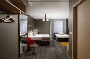 Una habitación de hotel moderna con una cama, un escritorio, una silla y un espejo.
