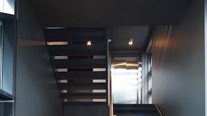 Una escalera moderna con barandilla de madera que lleva a una puerta blanca al final.