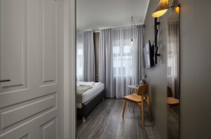 A modern hotel room with a bed, a desk, and a chair.
