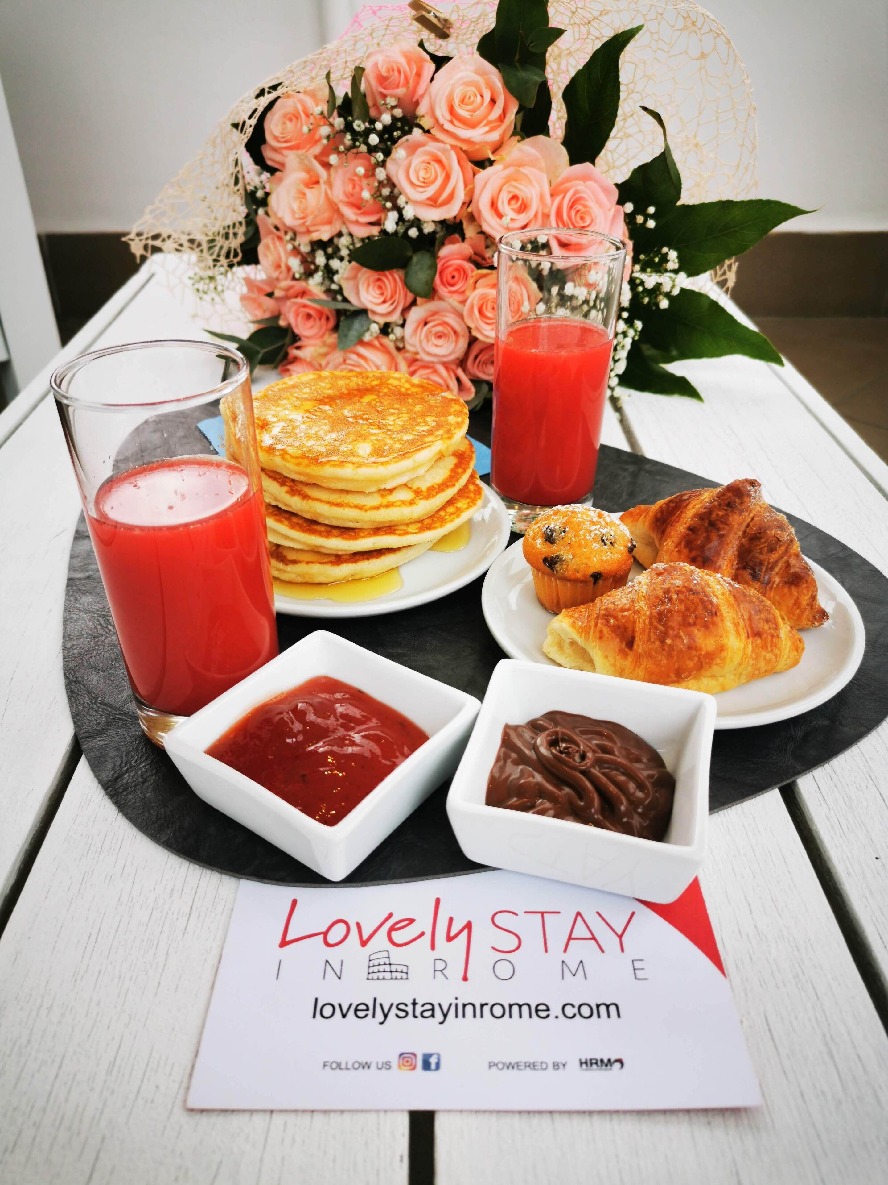 A breakfast setting with pancakes, croissants, and a bouquet of pink roses.