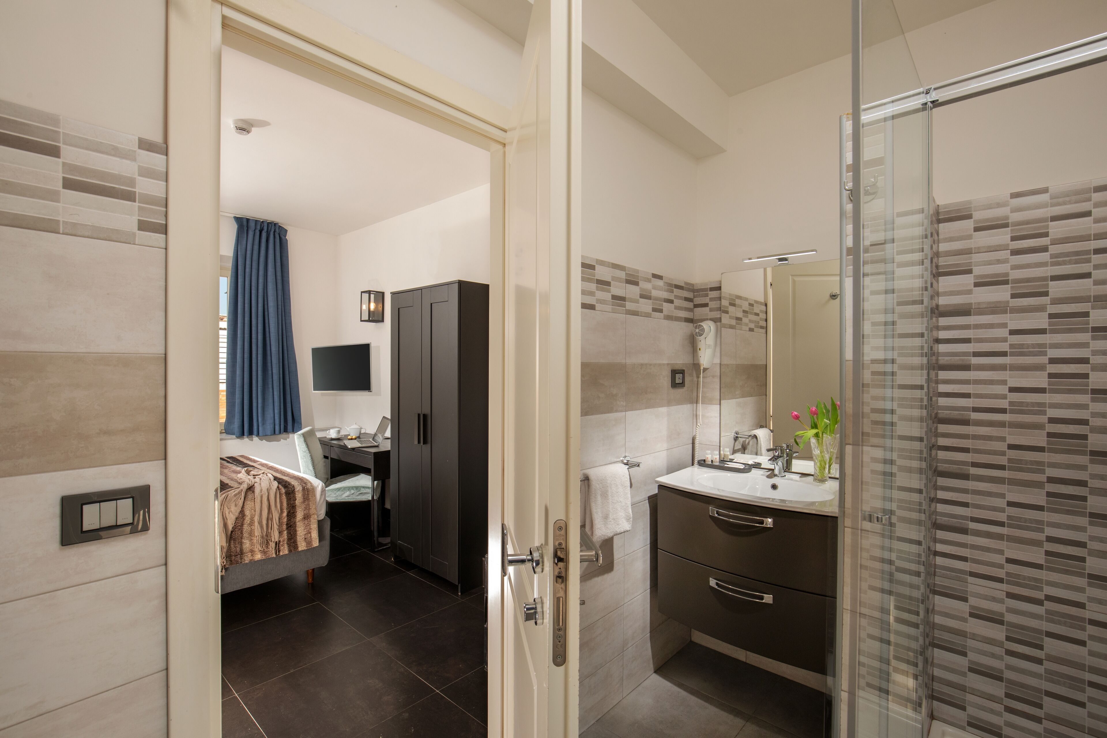 A modern hotel bathroom with a shower, a sink, and a mirror.