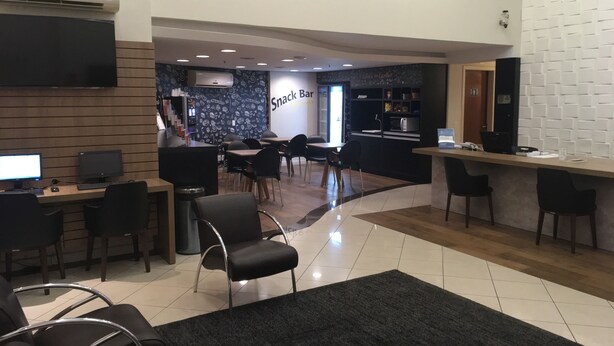 A modern snack bar with a counter, seating area, and a wall with a pattern. - Master Express Lima e Silva (Porto Alegre)
